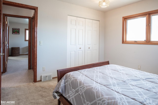 carpeted bedroom featuring a closet, visible vents, and baseboards