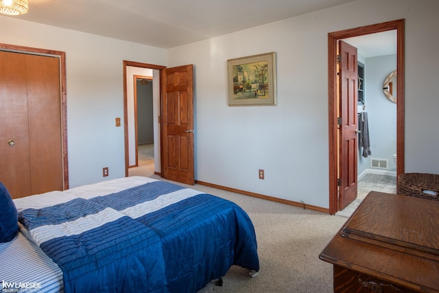 bedroom featuring baseboards, visible vents, ensuite bathroom, carpet, and a closet