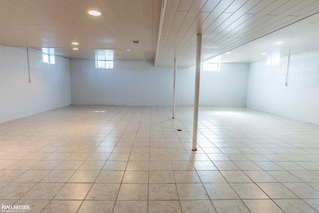 basement with light tile patterned flooring, concrete block wall, visible vents, and recessed lighting