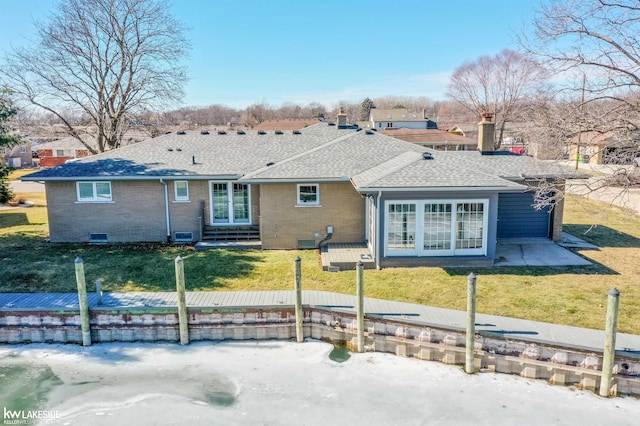 ranch-style home with a shingled roof, a front yard, and brick siding