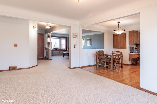 dining area with baseboards, visible vents, and light colored carpet