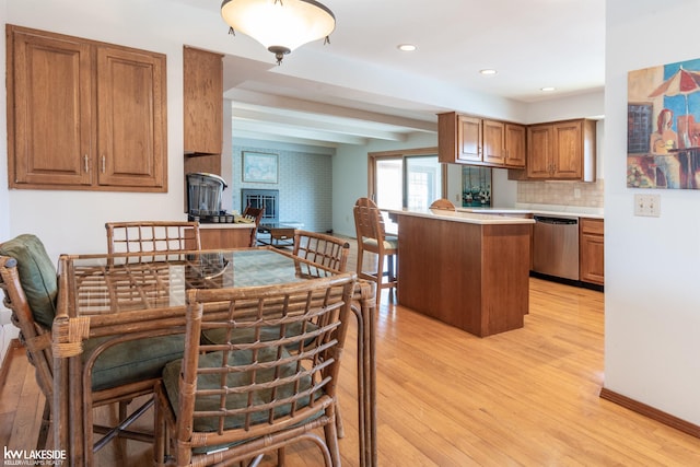 kitchen with light countertops, a fireplace, dishwasher, and light wood-style flooring