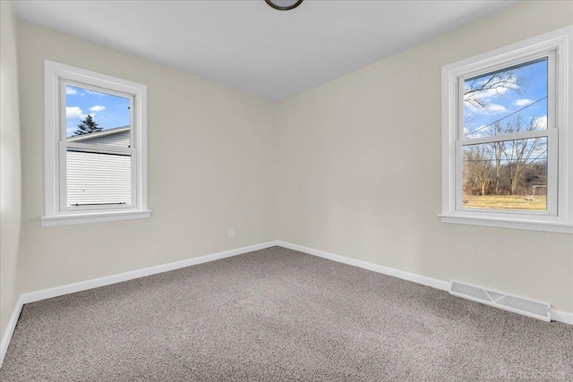 spare room featuring carpet floors, visible vents, and baseboards