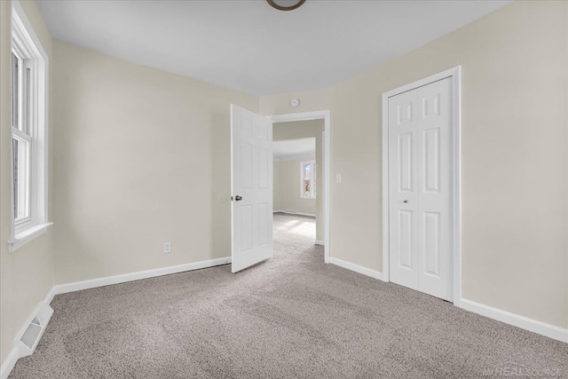 unfurnished bedroom featuring carpet, a closet, visible vents, and baseboards