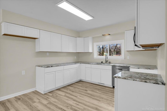 kitchen featuring stainless steel dishwasher, light stone counters, white cabinets, and a sink