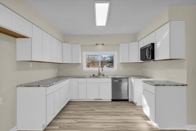 kitchen with light wood-style flooring, a sink, white cabinets, appliances with stainless steel finishes, and light stone countertops