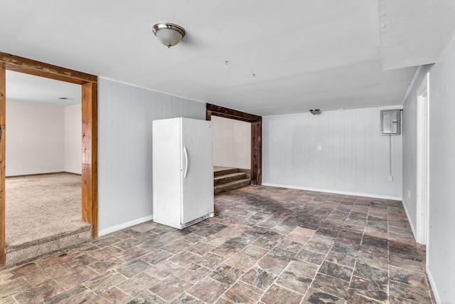 finished basement featuring freestanding refrigerator, stone finish flooring, baseboards, and stairs