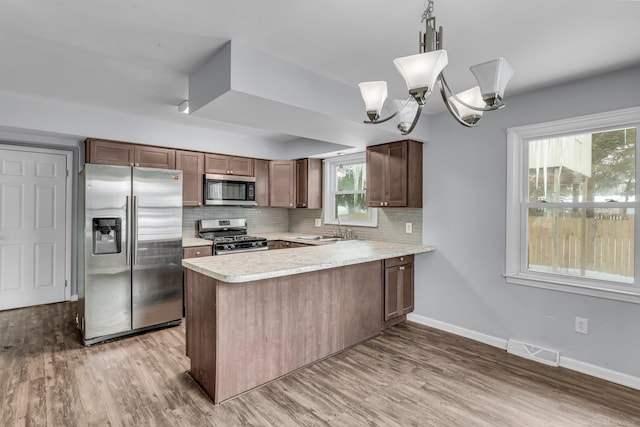 kitchen with stainless steel appliances, a sink, visible vents, light countertops, and tasteful backsplash