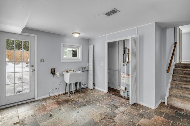 interior space featuring stairway, stone tile floors, visible vents, and baseboards