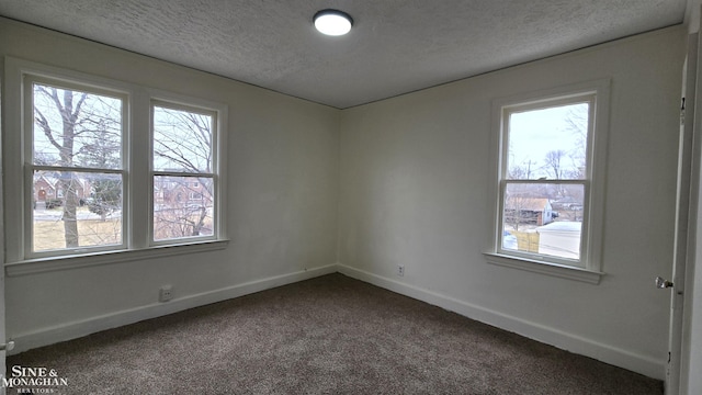 unfurnished room featuring baseboards, dark carpet, and a textured ceiling