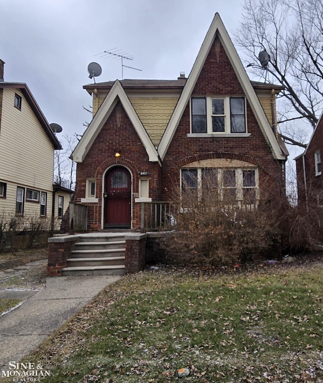 tudor-style house with a front yard and brick siding