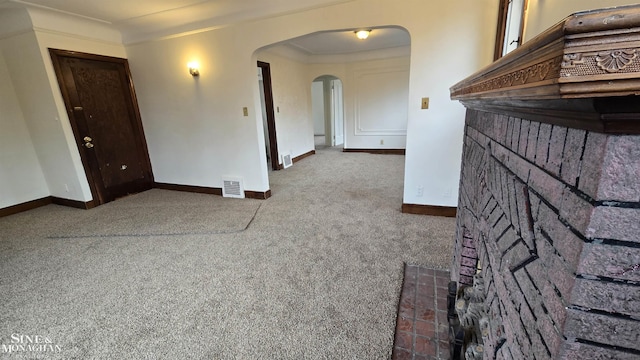 unfurnished living room featuring carpet floors, arched walkways, visible vents, and baseboards