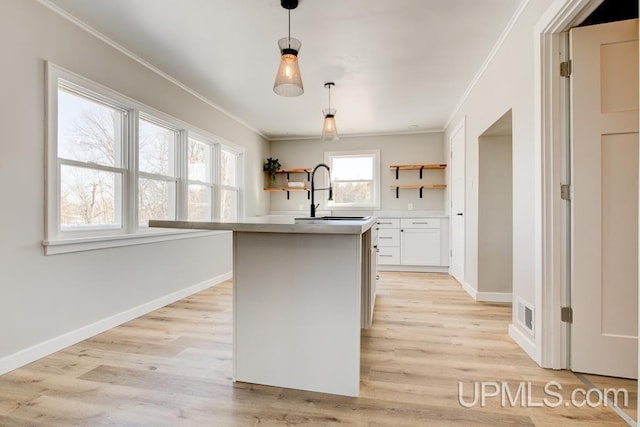 kitchen featuring a sink, light wood-style floors, ornamental molding, open shelves, and pendant lighting