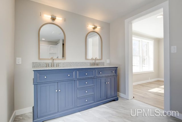 bathroom with double vanity, baseboards, and a sink