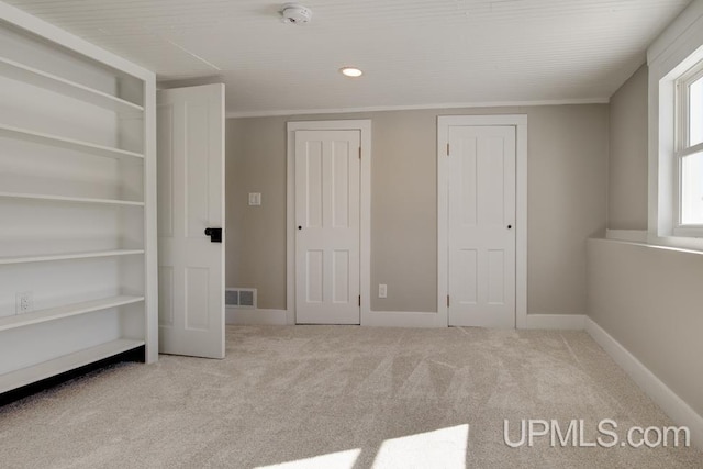 unfurnished bedroom with carpet, visible vents, and baseboards