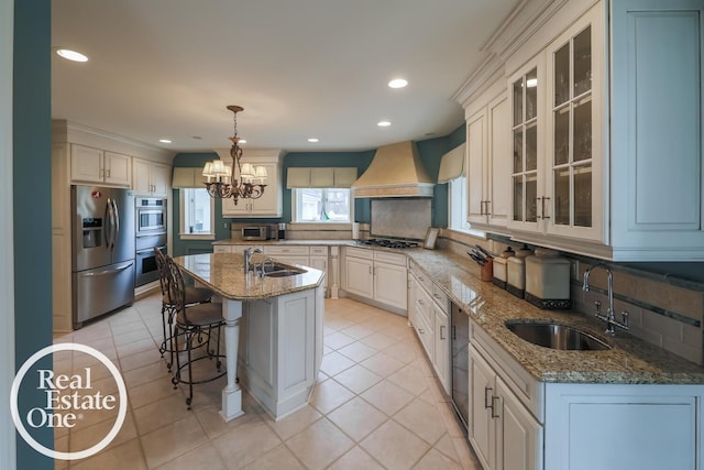 kitchen with premium range hood, a kitchen bar, stainless steel appliances, and a sink