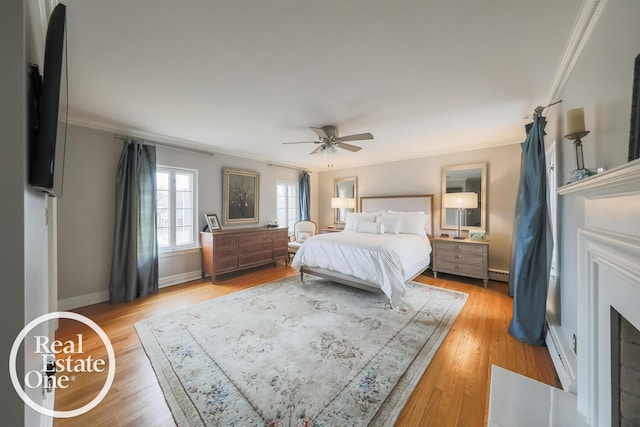 bedroom featuring a baseboard heating unit, baseboards, ornamental molding, and light wood finished floors