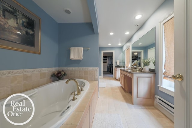 full bath with a walk in closet, a garden tub, recessed lighting, baseboard heating, and vanity