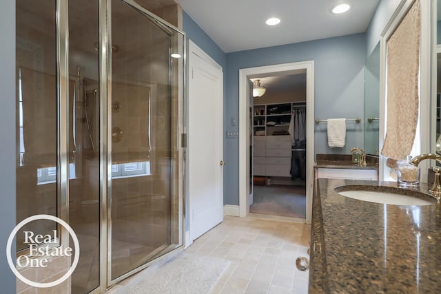 bathroom featuring a stall shower, a walk in closet, a sink, and recessed lighting