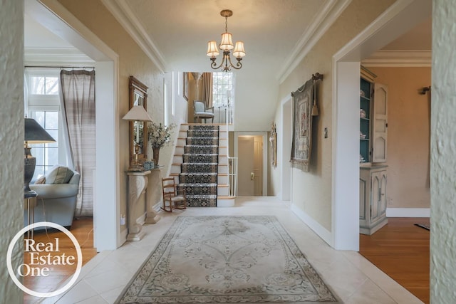 foyer entrance with baseboards, stairway, ornamental molding, tile patterned flooring, and a chandelier