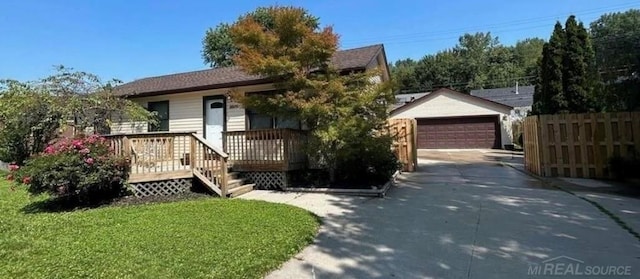 view of front of home with a garage, an outbuilding, fence, and a front yard