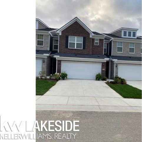 multi unit property featuring concrete driveway, brick siding, and an attached garage