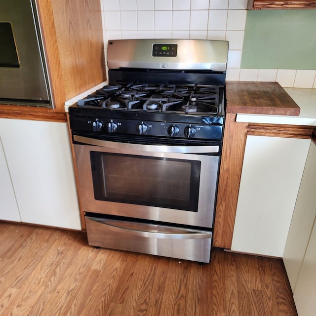 kitchen featuring wood finished floors, gas range, and decorative backsplash