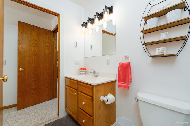 bathroom with toilet, baseboards, and vanity