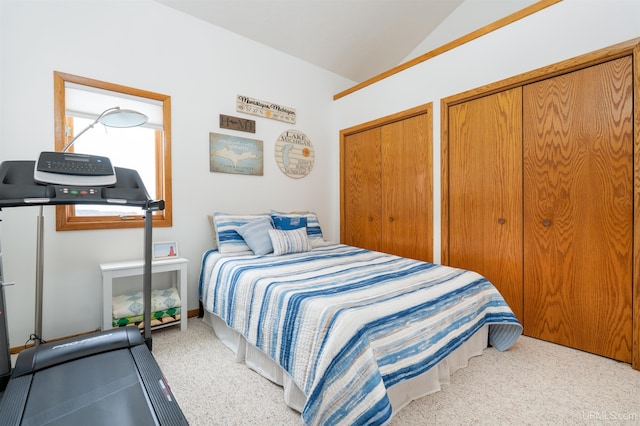 carpeted bedroom with vaulted ceiling and multiple closets