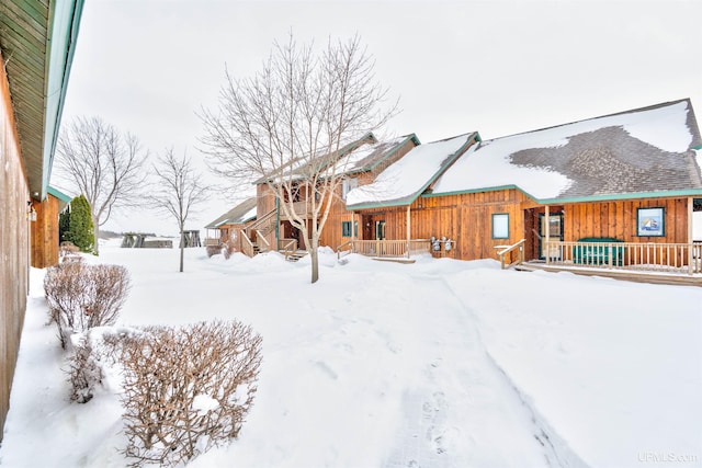 snow covered rear of property with a porch and board and batten siding