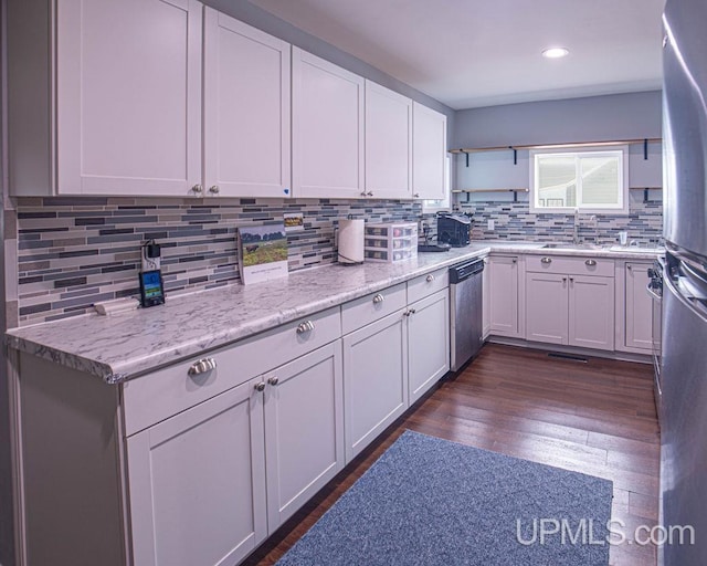 kitchen featuring dark wood finished floors, decorative backsplash, stainless steel appliances, white cabinetry, and a sink