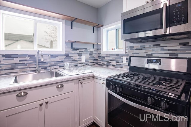 kitchen featuring a sink, stainless steel appliances, open shelves, and white cabinets