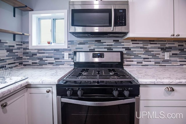 kitchen featuring stainless steel appliances, open shelves, white cabinetry, and decorative backsplash