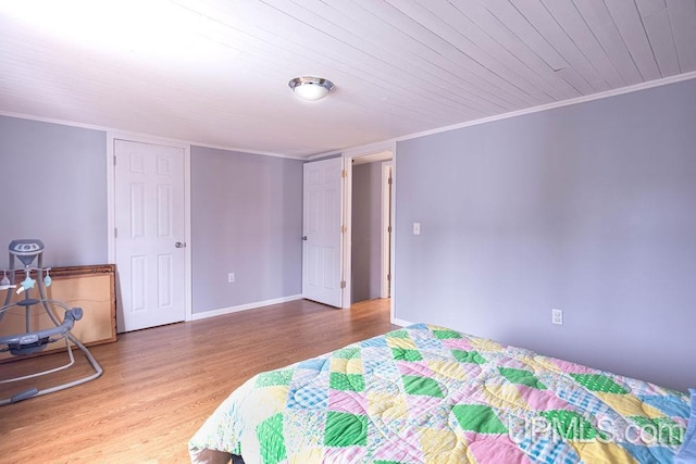 bedroom featuring baseboards, wood finished floors, wood ceiling, and crown molding