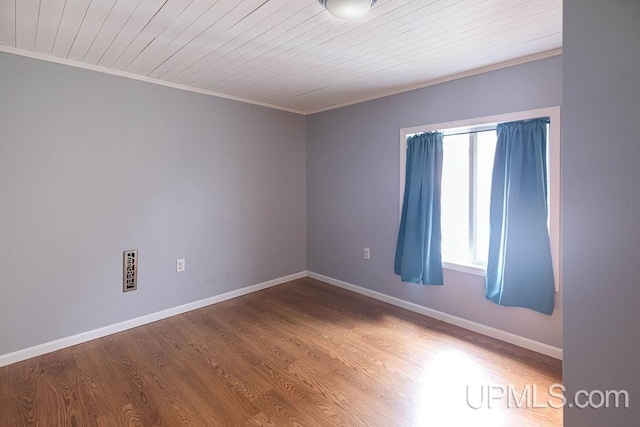 spare room featuring wood ceiling, crown molding, baseboards, and wood finished floors