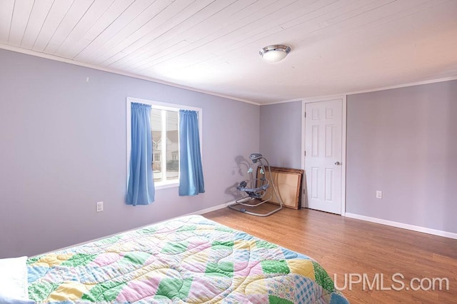 bedroom featuring baseboards, wood finished floors, wood ceiling, and crown molding