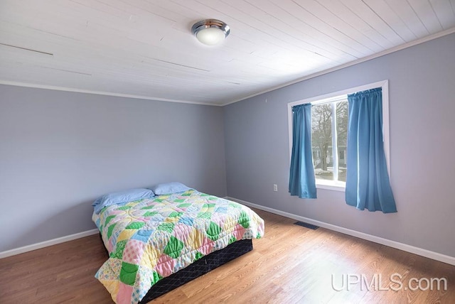 bedroom featuring baseboards, crown molding, visible vents, and wood finished floors