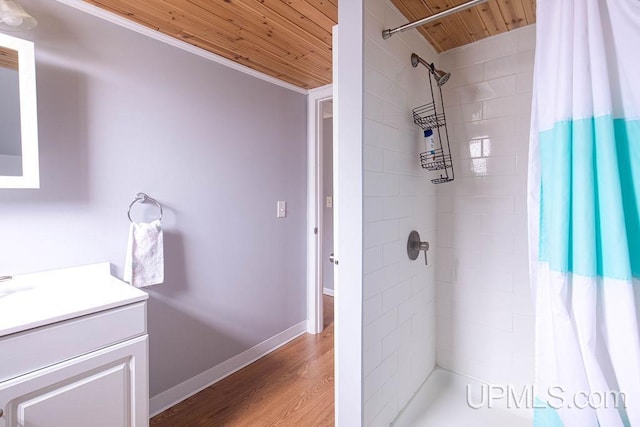 full bathroom featuring wooden ceiling, tiled shower, vanity, and wood finished floors