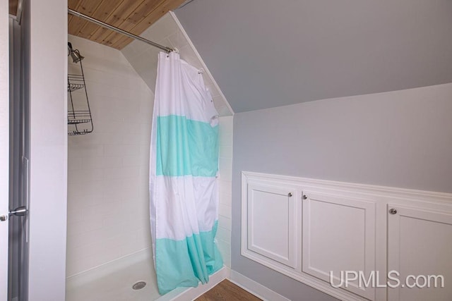 full bathroom with vaulted ceiling and a tile shower