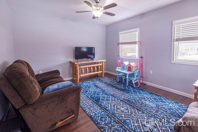 living room featuring a ceiling fan, baseboards, and wood finished floors