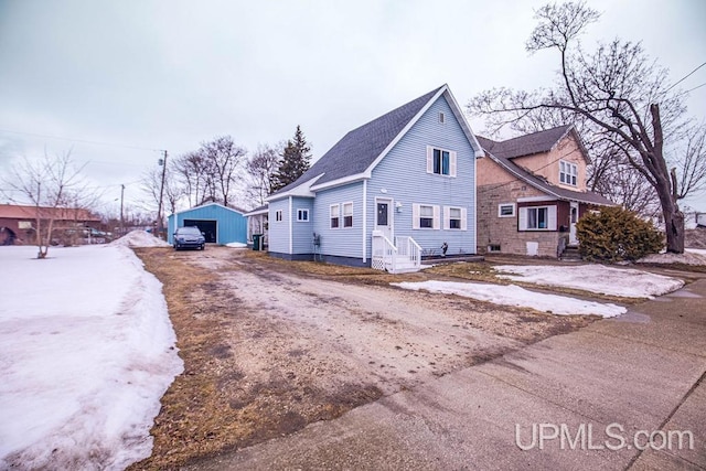 view of front of property with a shingled roof, an outbuilding, driveway, and a detached garage