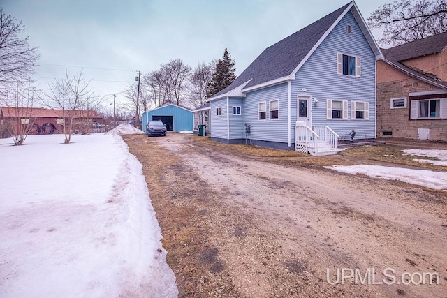 view of front of home with an outbuilding, roof with shingles, driveway, and a detached garage