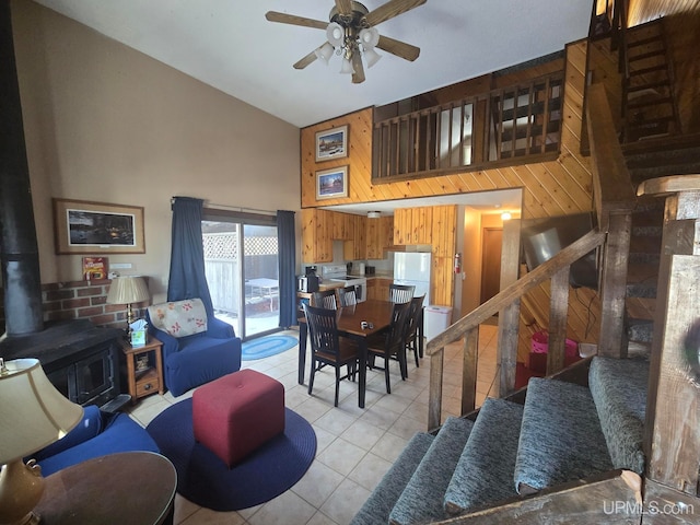 living area with a wood stove, light tile patterned floors, stairway, and high vaulted ceiling