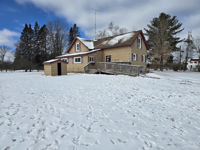 snow covered back of property featuring an outdoor structure and a deck