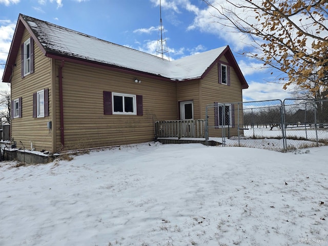 snow covered property with a garage and fence