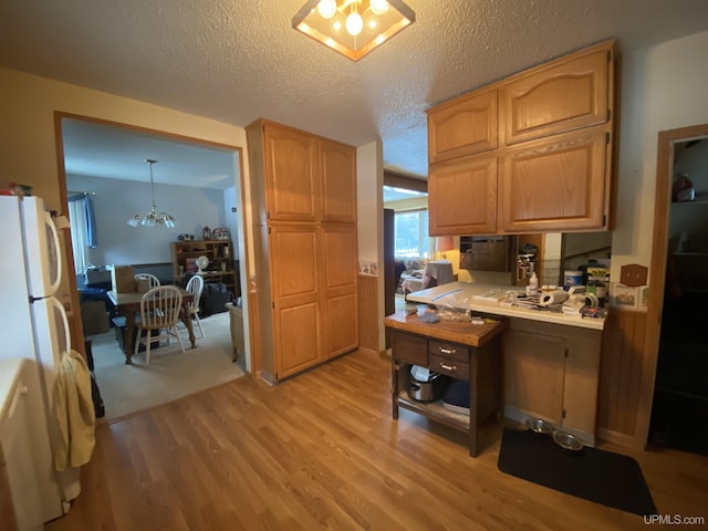 kitchen with light countertops, a notable chandelier, light wood finished floors, and a textured ceiling