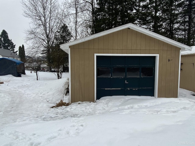 snow covered garage with a detached garage