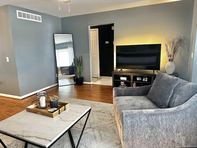 living area with wood finished floors, visible vents, and baseboards