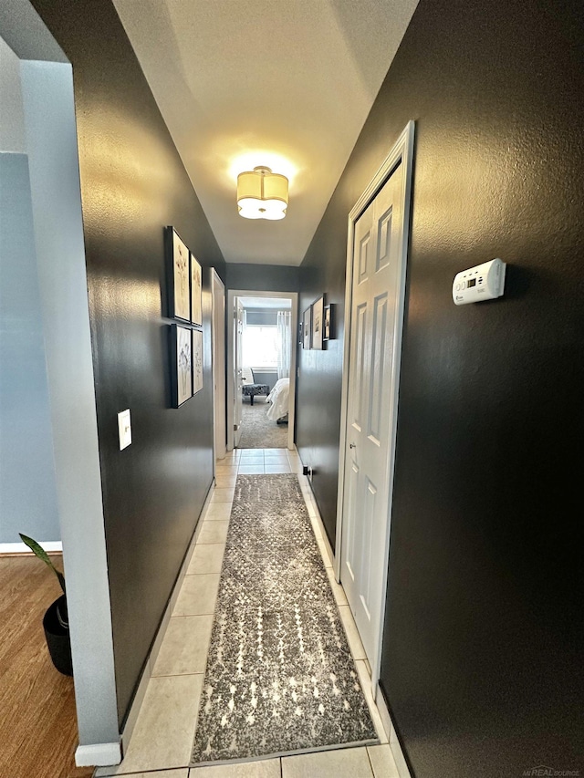 corridor with light tile patterned floors and baseboards