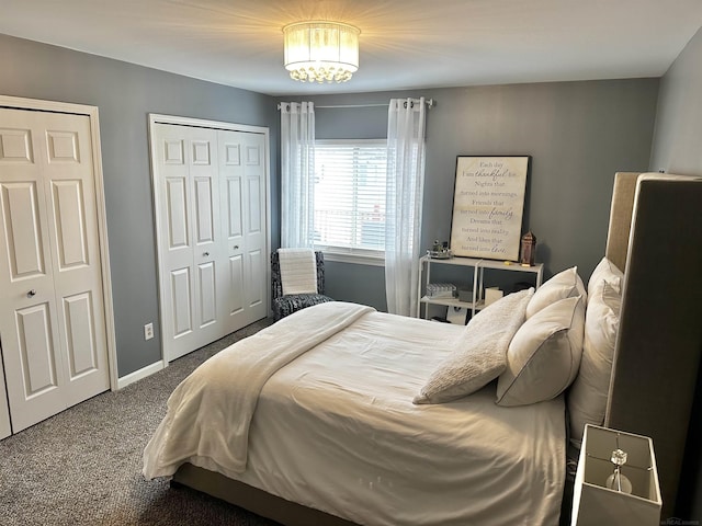 carpeted bedroom with a notable chandelier, baseboards, and multiple closets